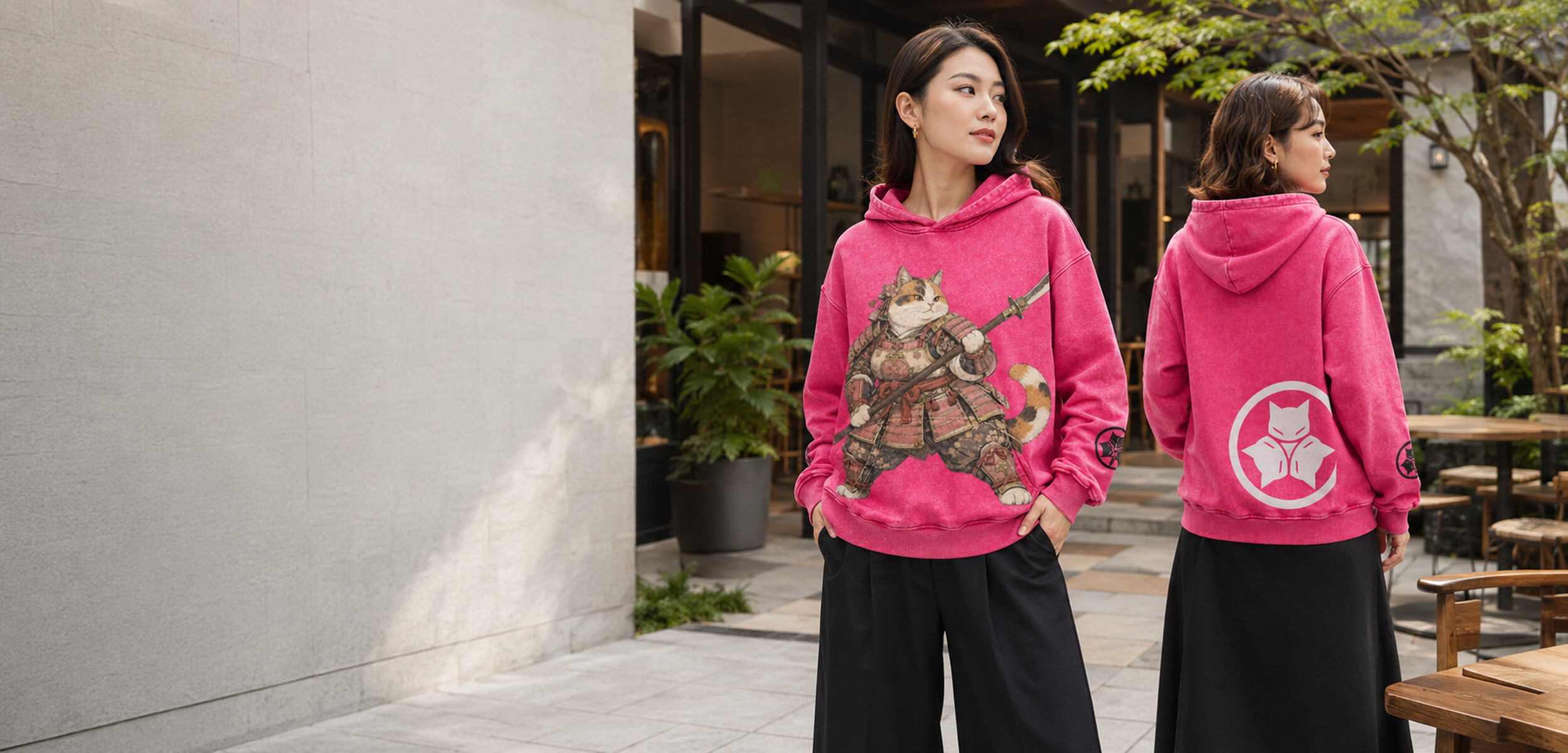 Two fashion models wearing the pink Alley Forms Onna-Musha hoodie, showing the front warrior artwork and rear crest