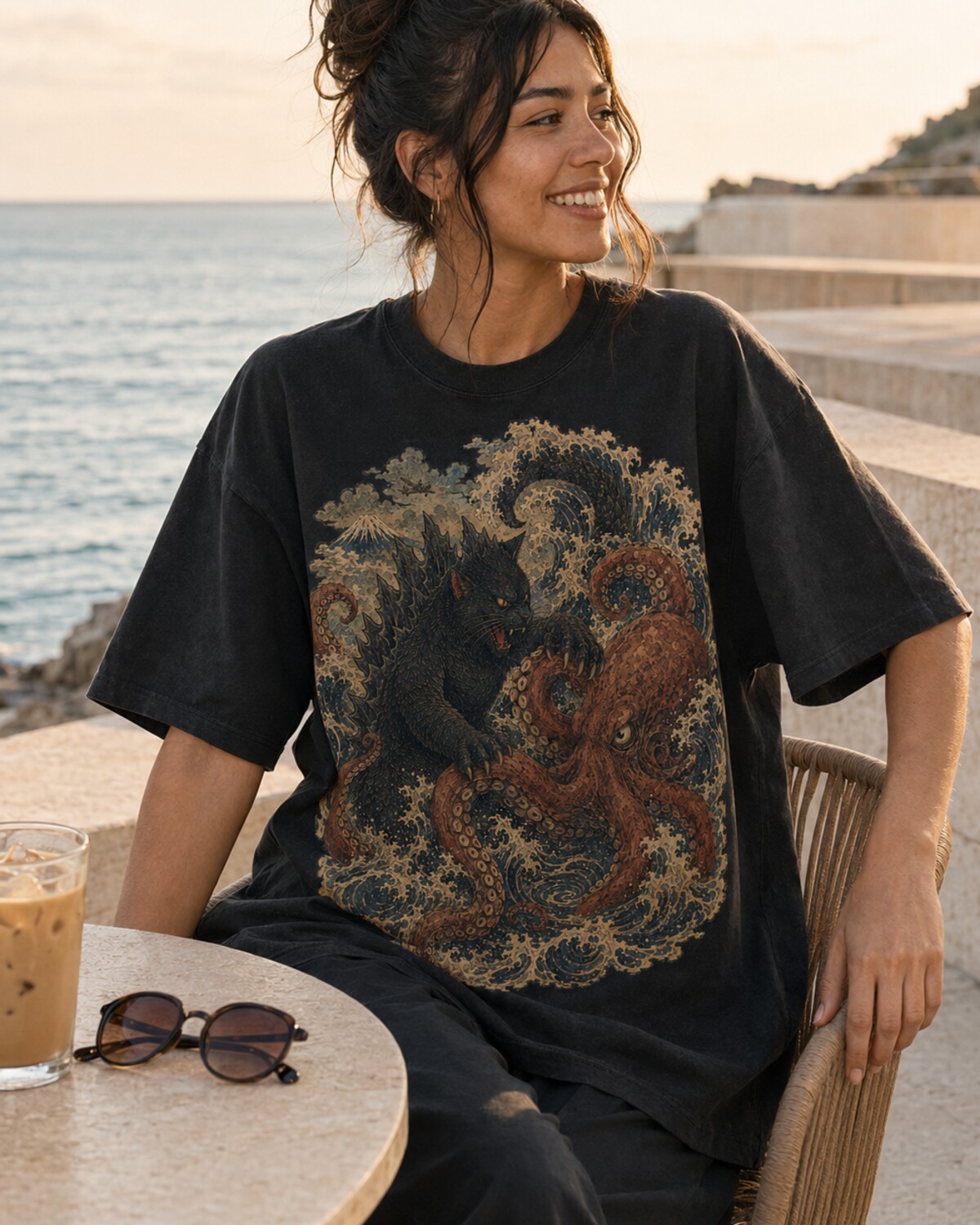 Model wearing the Catzilla versus Tako Titan tee at a seaside cafe